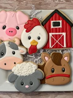 decorated cookies in the shape of farm animals and barnyards are on a plate