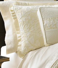 a close up of a bed with white sheets and pillow cases on top of it