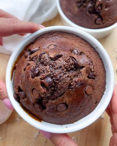 two hands holding white bowls filled with chocolate cake