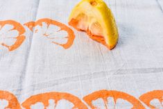 an orange cut in half sitting on top of a table cloth with leaves and flowers