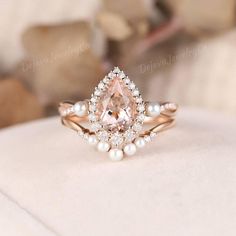 a pink diamond and pearl ring on top of a white cushion