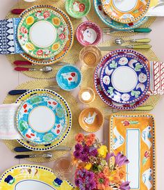 colorful plates and utensils laid out on a table with flowers in vases