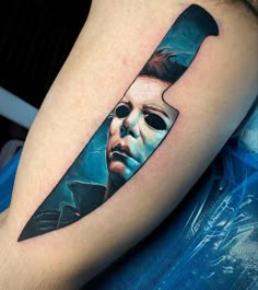 a knife tattoo on the arm of a person with a face and eyes painted on it