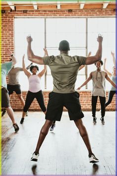 a group of people in a dance class with their arms up and hands behind their backs