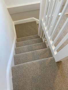 a staircase with carpeted steps leading up to the top floor and bottom handrail