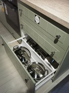 an open drawer in a kitchen with pots and pans