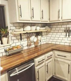 a kitchen with white cabinets and wooden counter tops