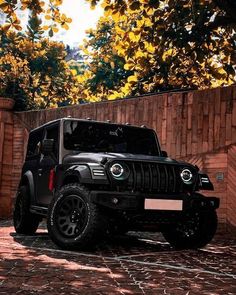 a black jeep parked in front of a brick wall