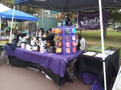 an outdoor market with purple table cloths and black tables topped with coffee mugs