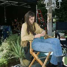 a woman sitting in a chair looking at her cell phone