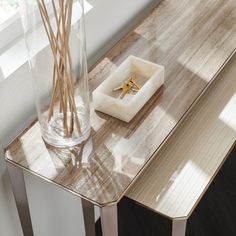 a glass vase sitting on top of a wooden table next to a box with two gold rings