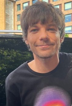 a man is smiling and wearing a black t - shirt with a rainbow design on it