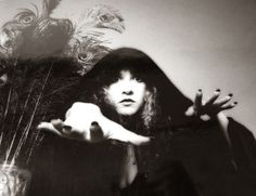 a black and white photo of a woman with feathers on her head