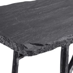 a close up view of a black table with metal legs and a gray stone top