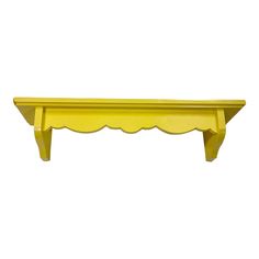 a yellow shelf with scalloped edges on it's sides, against a white background