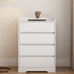 a white chest of drawers with a cup on top and a lamp next to it