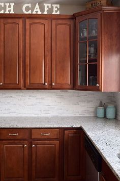 a kitchen with wooden cabinets and white marble counter tops, along with the words french cafe on the wall