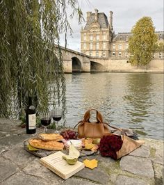 food and wine on the ground next to a river