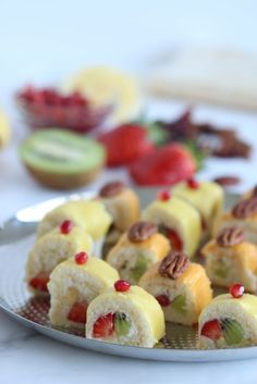 fruit sushi rolls on a plate with nuts and strawberries in the background, ready to be eaten