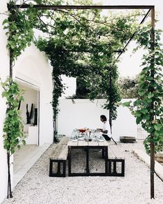 a person sitting at a table under an arbor