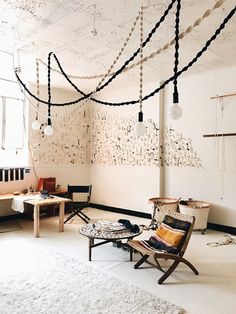 a living room filled with furniture and lots of lights hanging from the ceiling above it