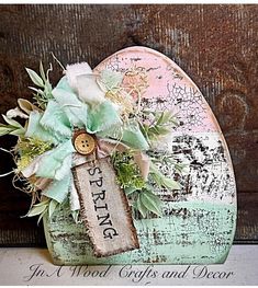 a heart shaped box with a tag on it and some flowers in the middle, sitting on top of a table