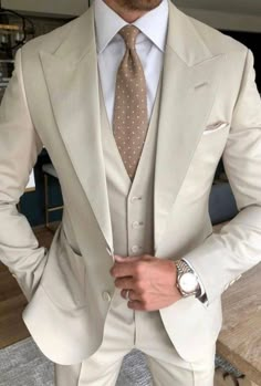 a man wearing a suit and tie standing in front of a table with his hands on his hips