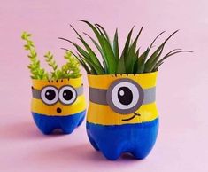 two yellow and blue planters with plants in them on a pink background, one is shaped like a minion