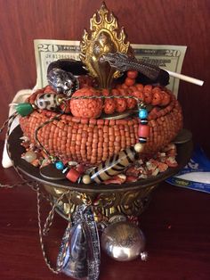 an elaborately decorated dish with beads and other items on it's stand, sitting on a wooden table