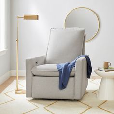 a chair with a blanket on it in a room next to a table and lamp