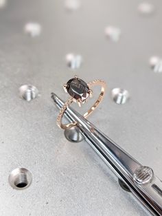 a diamond ring sitting on top of two metal tongs next to some screws