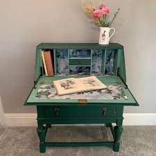 a green table with books and a vase on top