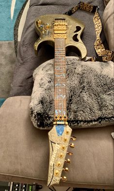 a gold guitar sitting on top of a chair next to a pillow and other items