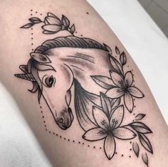 a black and white photo of a horse's head with flowers around it on the thigh