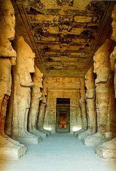 the interior of an ancient egyptian temple with carved columns and statues on either side of the entrance