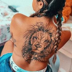 a woman with a lion tattoo on her back is sitting in front of a bed