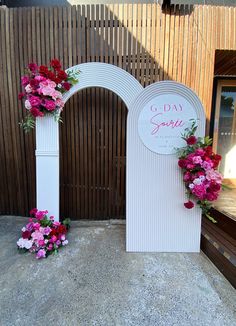 two white archways decorated with pink and red flowers