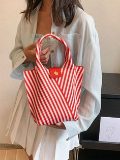 a woman is holding a red and white striped bag with an orange button on it