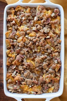 a casserole dish filled with meat and potatoes on top of a wooden table