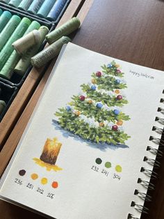 a christmas tree drawn in colored pencils next to some crayons