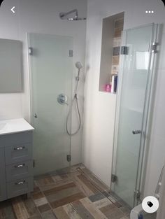 a bathroom with a walk in shower next to a white sink and mirror on the wall