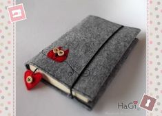 an open book with two red hearts attached to the front and back cover, sitting on top of a white table