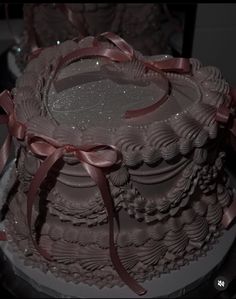 a large chocolate cake with pink ribbons on it's sides and two smaller cakes in the background