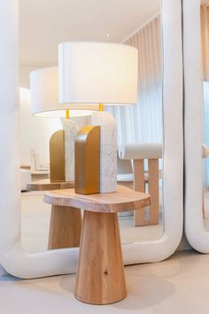 a wooden table sitting in front of a mirror with a lamp on top of it