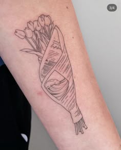 a woman's arm with a tattoo on it that has flowers wrapped in a ribbon