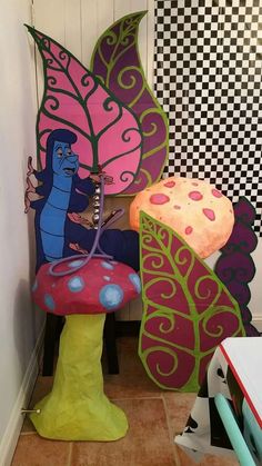 two colorful mushrooms sitting next to each other in a room with checkered wallpaper