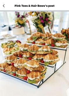 several trays with sandwiches on them sitting on top of a table next to flowers