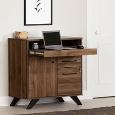 a laptop computer sitting on top of a wooden desk next to a wall mounted painting