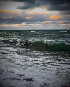 the ocean with waves crashing on it under a cloudy sky