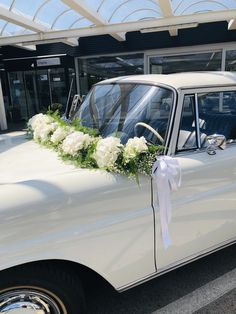 an old white car is decorated with flowers and greenery for a wedding or special event